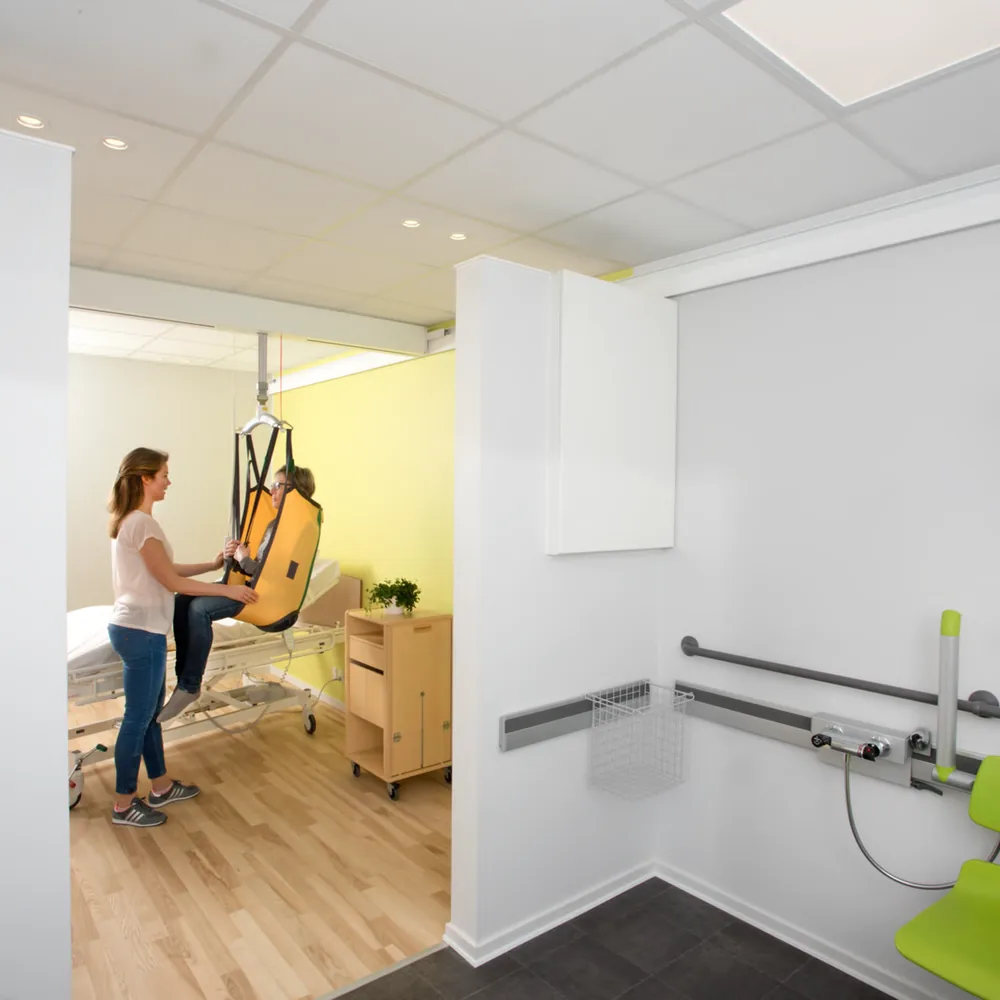 Habitación de residencia con grúa de techo y raíl hasta el baño